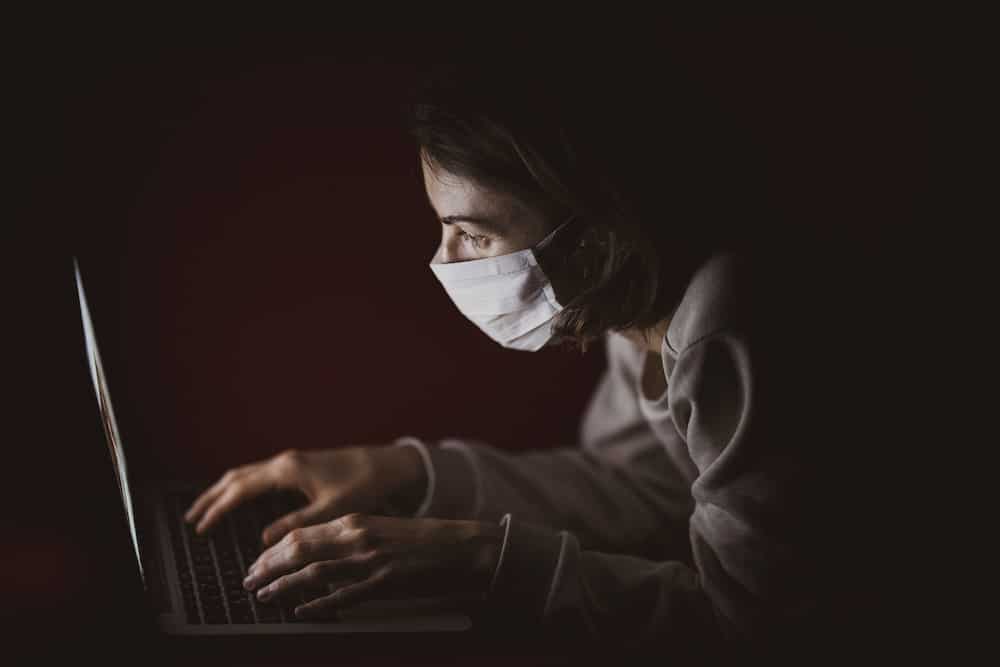 woman searching symptoms for covid-19 sore throat on laptop