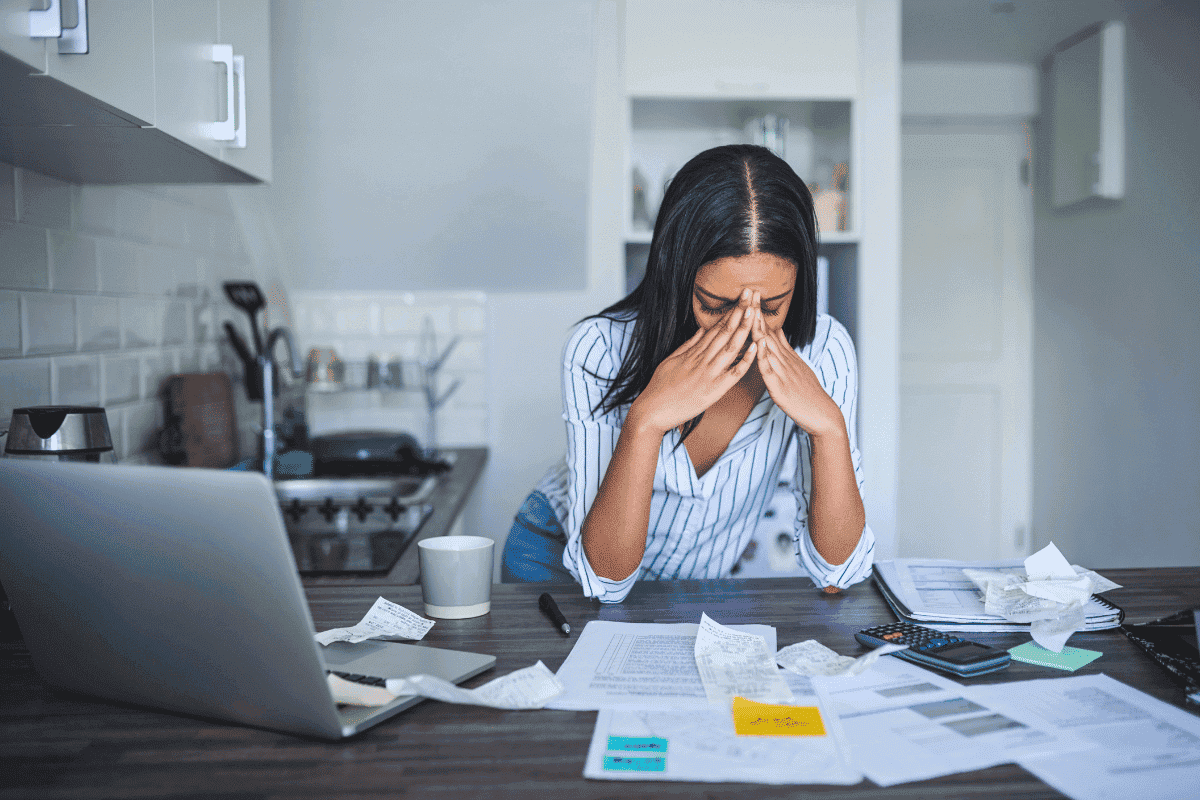 Woman stressed surrounded by papers and laptop